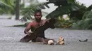 Seorang lelaki menggunakan kayu sebagai perahu saat banjir melanda Sri Lanka, Minggu (28/5). Saat ini tercatat sudah ada 122 orang yang kehilangan nyawanya akibat bencana yang dipicu oleh hujan lebat di Sri Lanka. (AP Photo)