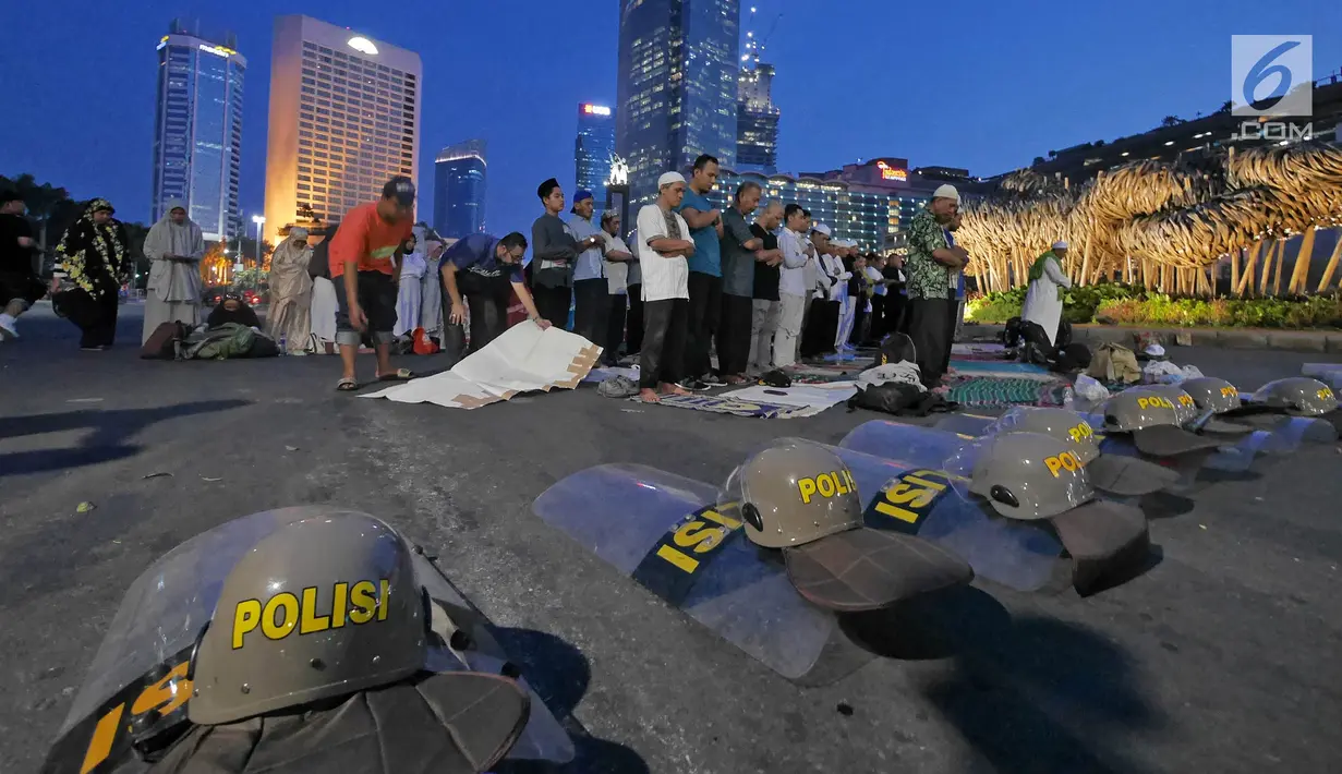 Massa Gerakan Nasional Kedaulatan Rakyat melaksanakan salat magrib di sela aksi unjuk rasa di depan kawasan Bundaran HI, Jakarta, Selasa (21/5/2019). Dalam aksinya, mereka Bawaslu memeriksa hasil Pemilu 2019 yang dinilai banyak terdaopat kecurangan. (Liputan6.com/Herman Zakharia)