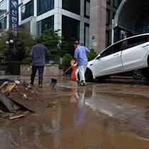 Sebuah mobil yang rusak akibat banjir terlihat di jalan setelah hujan deras di distrik Gangnam, Seoul pada Selasa (9/8/2022). Di distrik Gangnam yang mewah dan sangat terkonsentrasi, beberapa bangunan tanpa listrik dan telah terendam air, sementara mobil, bus, dan stasiun kereta bawah tanah terendam, membuat orang-orang terdampar. (YONHAP / AFP)
