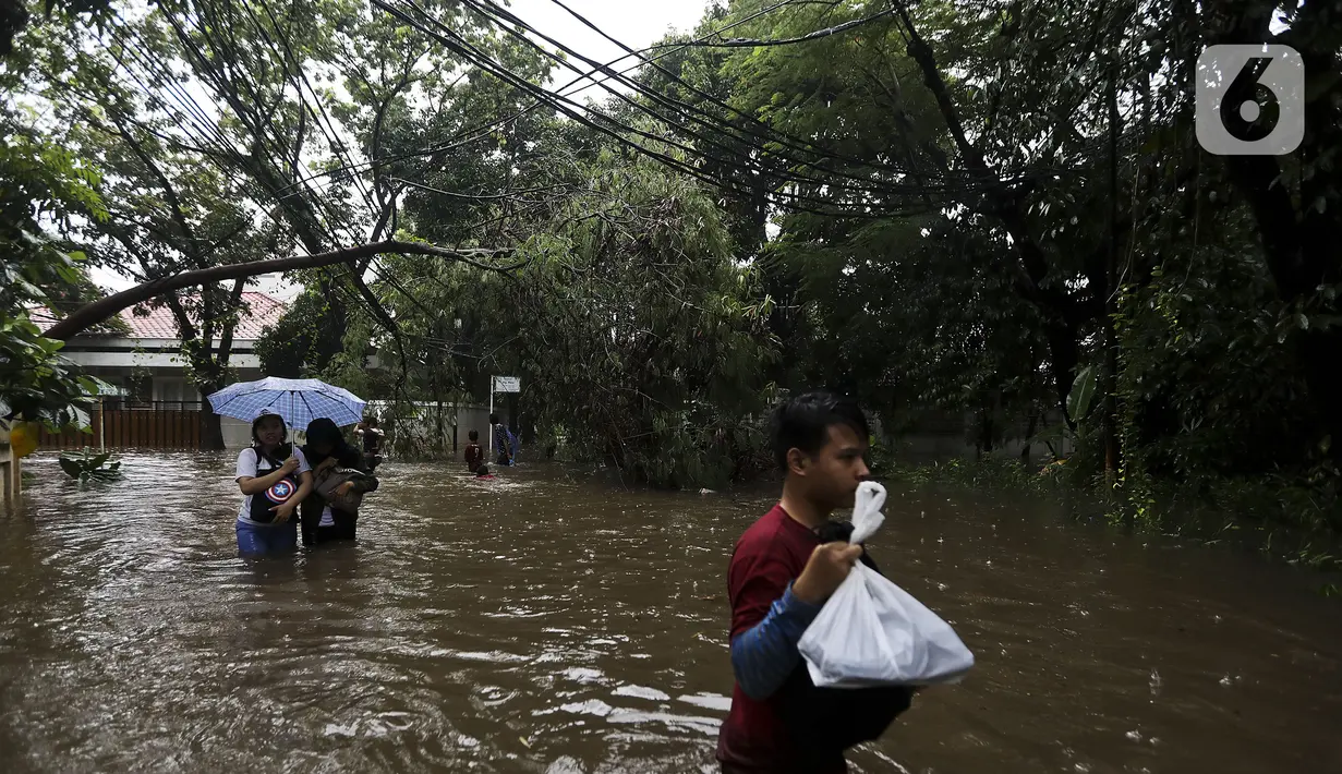 Warga melintasi banjir di Jalan Hang Lekir, Kebayoran Lama, Jakarta Selatan, Rabu (1/1/2020). Banjir tersebut disebabkan karena tingginya intensitas hujan yang mengguyur sejak Selasa (31/12/2019). (Liputan6.com/Johan Tallo)
