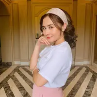 Kaus berwarna putih, entah itu polos atau yang memiliki motif atau tulisan tertentu, juga bisa terlihat manis, seperti terlihat pada Prilly di foto ini. Kamu hanya perlu menambahkan sedikit aksesori, seperti bando atau menata rambut dengan gaya yang lebih heboh dari biasanya. Foto: Instagram.