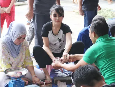 Penyanyi dangdut Ayu Ting Ting ikut memotong daging kurban ditemanin ibunya Umi Kalsum di kediamannya, Depok (1/9). Pada tahun ini Ayu Ting Ting berkurban sapi sebanyak 3 ekor di kediamannya. (Liputan6.com/Herman Zakharia)