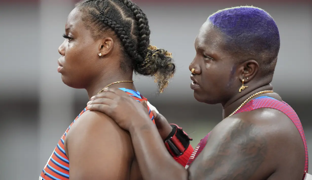 Atlet tolak peluru Amerika Serikat, Raven Saunders dan rekan setimnya Jessica Ramsey menyaksikan saingan mereka selama babak kualifikasi pukulan putri di Olimpiade Musim Panas di Tokyo, Jumat (30/7/2021). (AP Photo/Matthias Schrader)