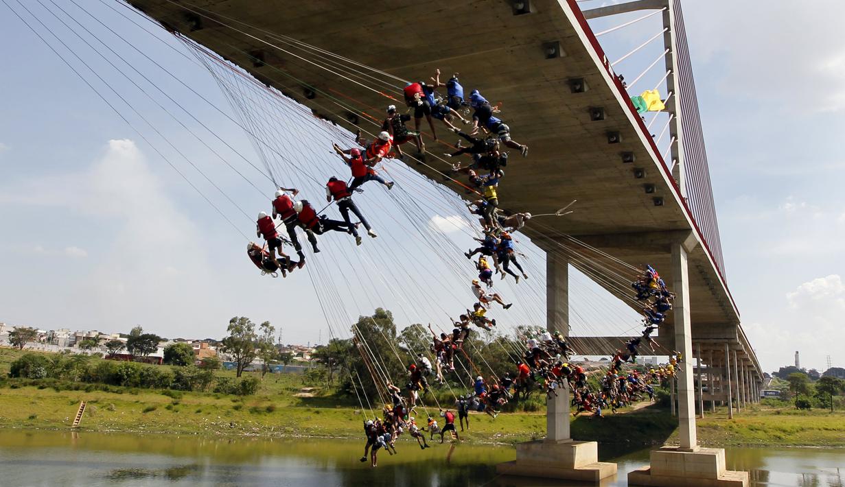 Ratusan orang menggunakan seutas tali melompat dari jembatan berketinggian 30 meter di Hortolandia, Brasil, Minggu (10/4). Sebanyak 149 orang mencoba membuat rekor dunia dengan melompat bersama dari atas jembatan. (REUTERS/Paulo Whitaker)