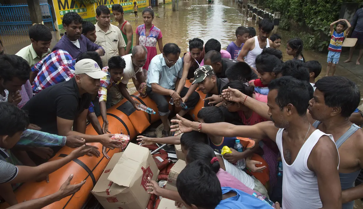 Petugas membagikan makanan kepada korban banjir di Gauhati, India, Rabu (14/6). Angin monsun yang mendatangi India berdampak pada tingginya curah hujan yang menyebabkan banjir. (AP Photo / Anupam Nath)