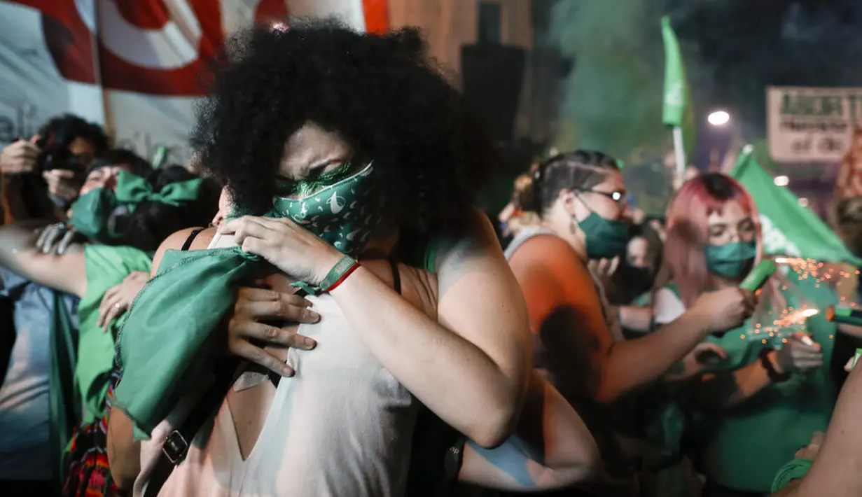 Aktivis hak-hak aborsi berpelukan sambil menangis setelah anggota parlemen menyetujui undang-undang yang melegalkan aborsi di luar Kongres, Buenos Aires, Argentina, Rabu (30/12/2020). Ini merupakan puncak bagi para aktivis perempuan setelah bertahun-tahun lamanya. (AP Photo/Natacha Pisarenko)