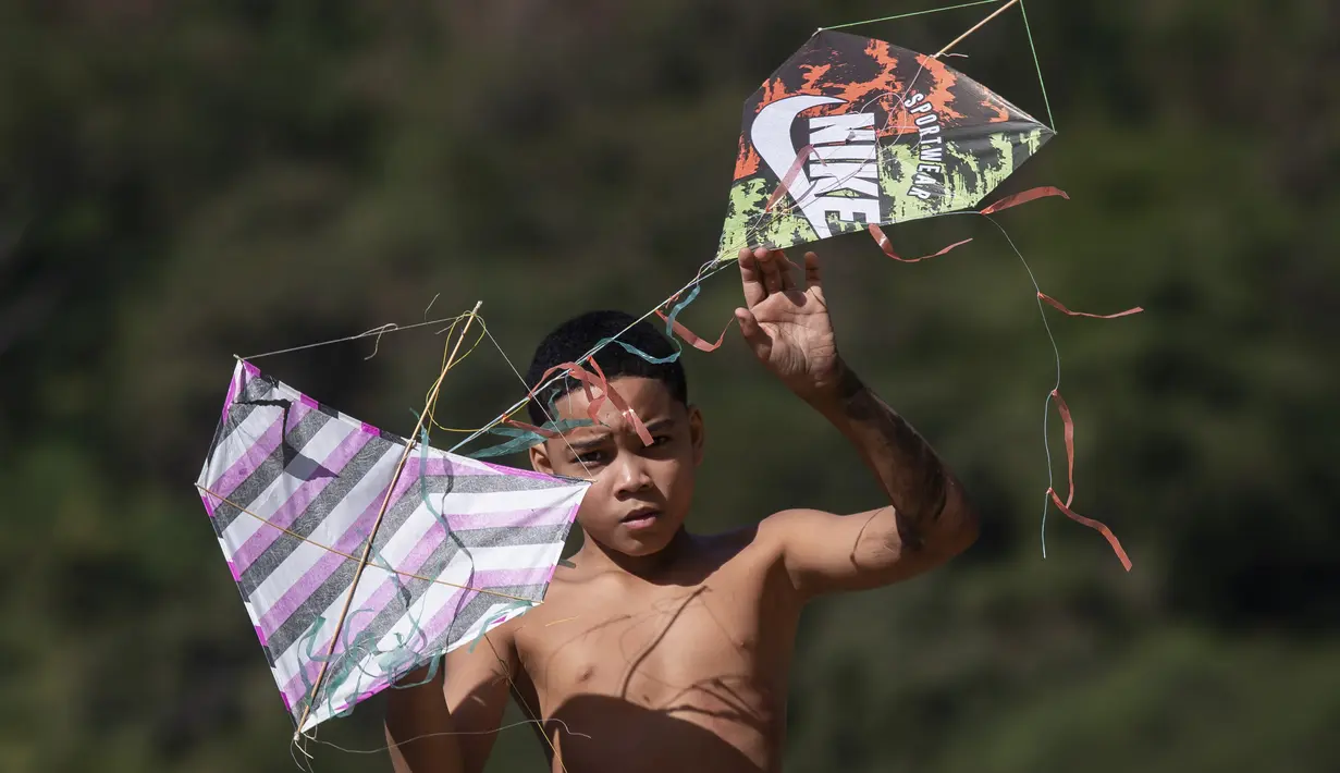 Seorang pemuda memegang layang-layang saat festival di favela Turano di Rio de Janeiro, Minggu, 7 Juli 2024. (AP Photo/Bruna Prado)