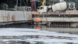 Aktivitas pekerja dekat limbah busa yang mencemari Kali Ancol, Jakarta Utara, Rabu (16/3/2022). Munculnya busa tersebut diduga berasal dari limbah rumah tangga dan industri akibat belum efektifnya Instalasi Pengolahan Air Limbah (IPAL). (merdeka.com/Iqbal S. Nugroho)