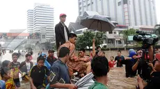 Memantau banjir sambil berdiri di atas gerobak. (Liputan6.com/Helmi Fithriansyah)