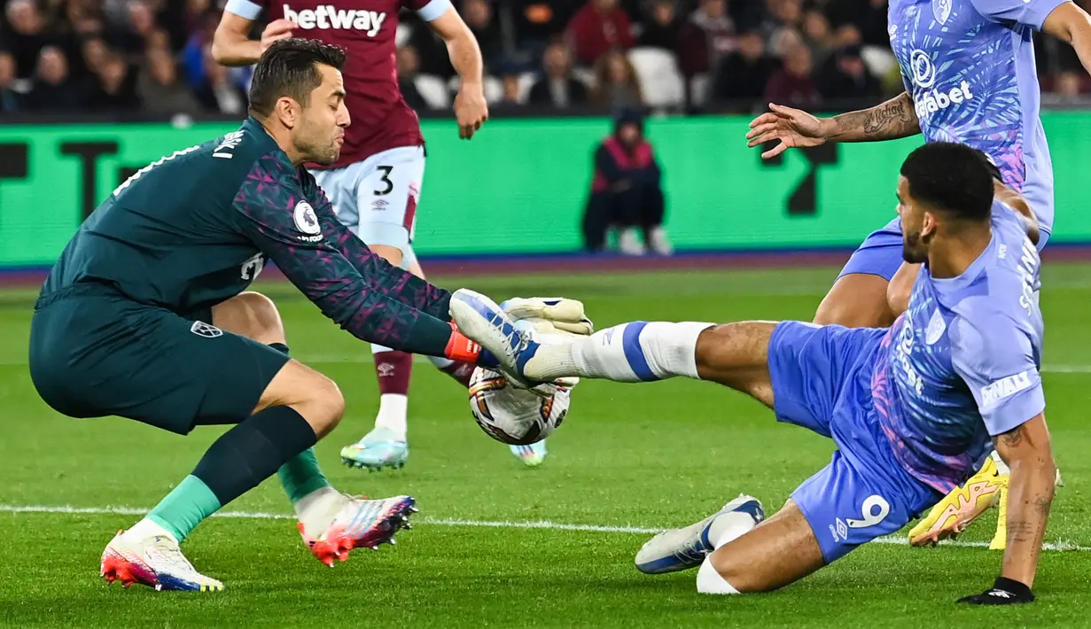 Kiper West Ham United Lukasz Fabianski (kiri) menghentikan bola yang ditembakkan oleh striker Bournemouth Dominic Solanke pada pekan ke-13 ajang Premier League di Stadion Olimpiade London, Selasa (25/10/2022) dini hari WIB. West Ham menempati peringkat ke-10 dengan torehan 14 poin dari 12 pertandingan. (Photo by Glyn KIRK / AFP)