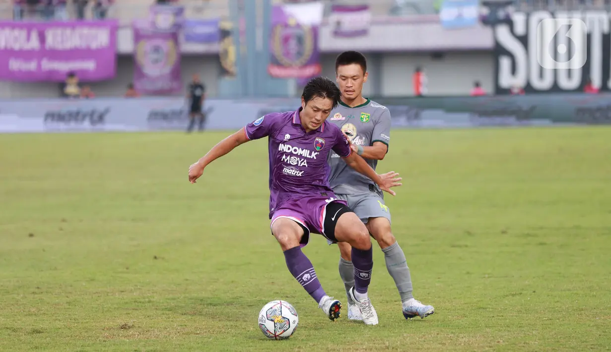 Pemain Persebaya Surabaya, Sho Yamamoto, berusaha melewati pemain Persita Tangerang, Bae Sin-yeong, pada laga Liga 1 di Stadion Indomilk Arena, Tangerang, Rabu (18/1/2023). Persebaya menang dengan skor 5-0. (Bola.com/M Iqbal Ichsan)