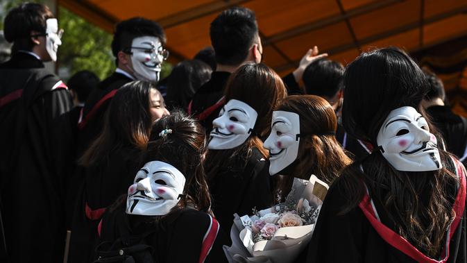 Mahasiswa mengenakan topeng Guy Fawkes selama aksi protes pada upacara kelulusan mereka di Chinese University of Hong Kong, Hong Kong, Kamis (7/11/2019). Sekitar seribu mahasiswa mengabaikan larangan mengenakan topeng yang dikeluarkan pemerintah pada Oktober 2019. (Philip FONG / AFP)