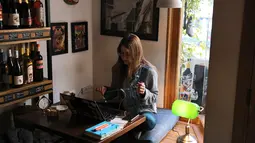 Seorang perempuan duduk dengan laptopnya di sebuah kafe di Beirut pada 14 Januari 2022. Kafe-kafe Beirut sekarang berfungsi sebagai tempat kerja pengganti bagi orang-orang yang bergulat dengan kekurangan listrik dan pemutusan internet yang berasal dari krisis ekonomi. (JOSEPH EID / AFP)