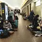 Orang-orang duduk di kereta bawah tanah Kiev, menggunakannya sebagai tempat perlindungan bom di ibu kota Ukraina, Kamis, 24 Februari 2022. Warga di Kiev tampak berlindung di stasiun bawah tanah kota dan tempat-tempat aman lainnya untuk menghindari invasi Rusia. (AP Photo/Emilio Morenatti)