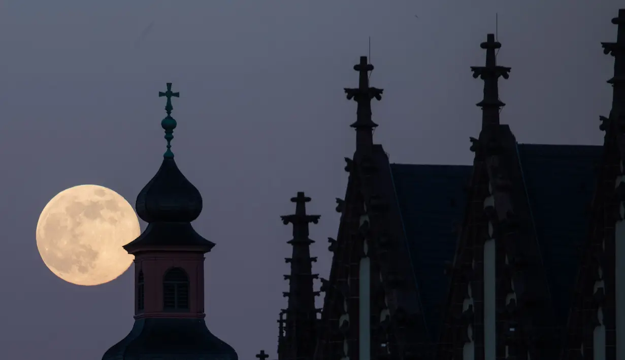 Bulan purnama tampak di belakang gereja Deutschorden dan atap gereja Dreikönig di Frankfurt am Main, Jerman barat, (10/5). (AFP Photo/dpa/Frank Rumpenhorst/Germany Out)
