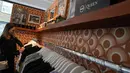 Seorang wanita melihat t-shirt di toko baru yang didedikasikan untuk menjual merchandise resmi band rock Queen sebelum dibuka di London, Senin (27/9/2021). Queen membuka toko pop-up di Carnaby Street pada minggu ini untuk menandai lima dekade mereka di kancah musik. (AP Photo/Alastair Grant)