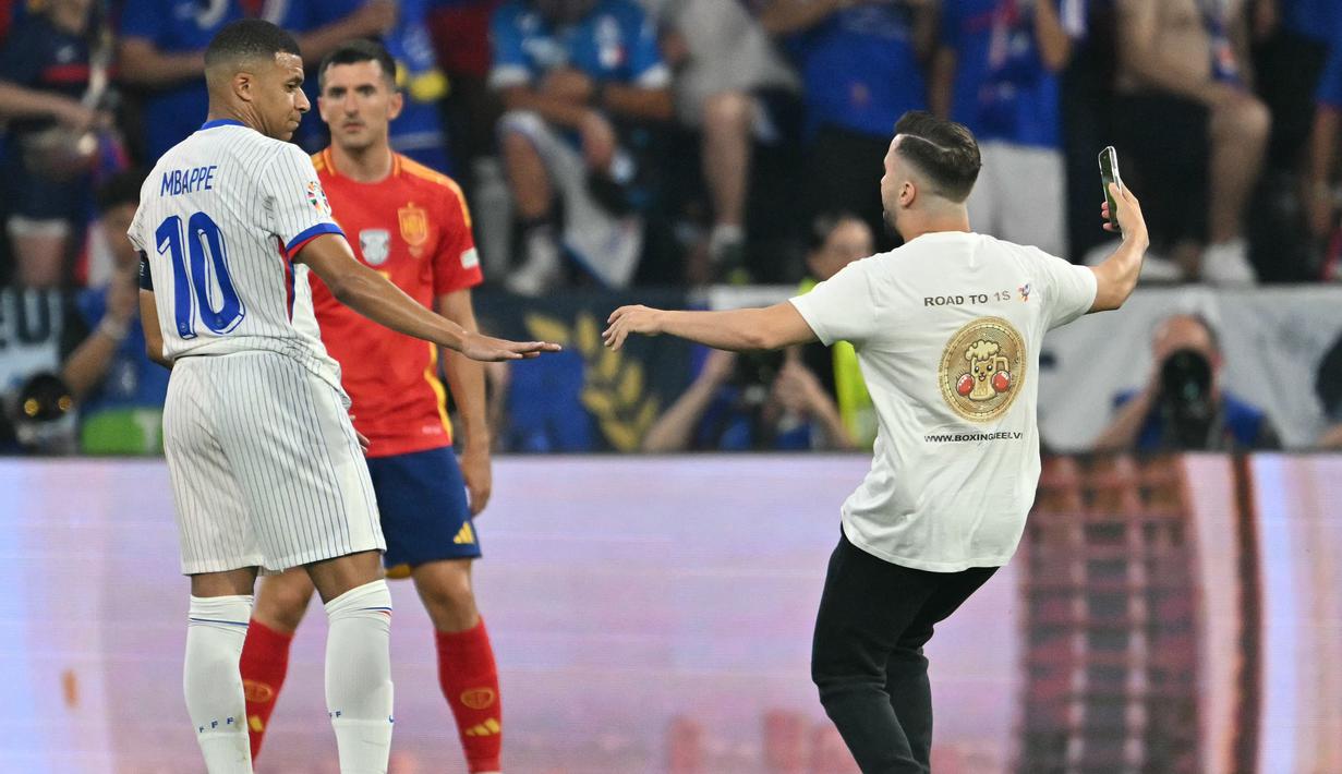 Penyerbu lapangan berhasil menghindari keamanan saat ia berlari ke arah bintang Prancis Kylian Mbappe, dengan wasit terpaksa menghentikan pertandingan. (MIGUEL MEDINA / AFP)