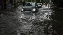 Sejumlah mobil melewati jalan yang tergenang air di tengah hujan lebat di Kolkata (20/9/2021). Hujan dilaporkan dipicu oleh sirkulasi siklon yang terbentuk di atas Teluk Benggala. (AFP/Dibyangshu Sarkar)