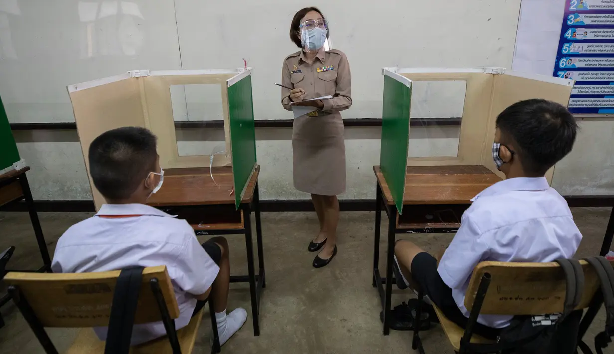 Seorang guru dengan pelindung wajah mengajar siswanya di sebuah kelas di Samkhok School di Pathum Thani, Bangkok, Rabu (1/7/2020). Thailand telah memulai fase kelima relaksasi pembatasan covid-19 yang memungkinkan kembali dibukanya sekolah-sekolah setelah ditutup sejak Maret lalu. (AP/Sakchai Lalit)