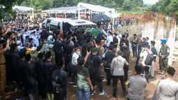 Anggota Brimob Polda Jabar membawa peti jenazah almarhum putra sulung Gubernur Jawa Barat, Emmeril Kahn Mumtadz saat prosesi pemakaman di Cimaung, Banjaran, Kabupaten Bandung, Jawa Barat, Senin (13/6/2022). Ribuan warga dan siswa berseragam sekolah juga memadati bagian-bagian pinggir jalan menuju ke lokasi pemakaman Eril. (TIMUR MATAHARI / AFP)