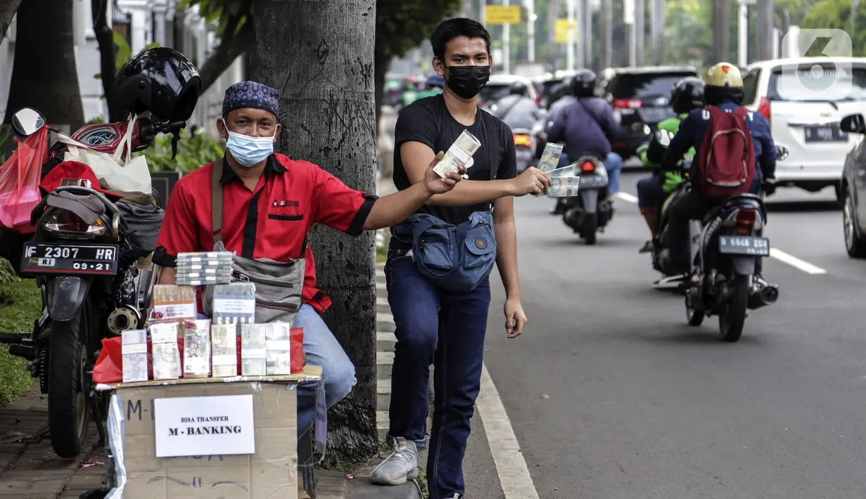 Penjual jasa penukaran uang menawarkan uang baru dalam berbagai pecahan di kawasan Pondok Indah, Jakarta, Kamis (6/5/2021). Penjual jasa musiman tersebut mulai ramai menjelang Lebaran. (Liputan6.com/Johan Tallo)