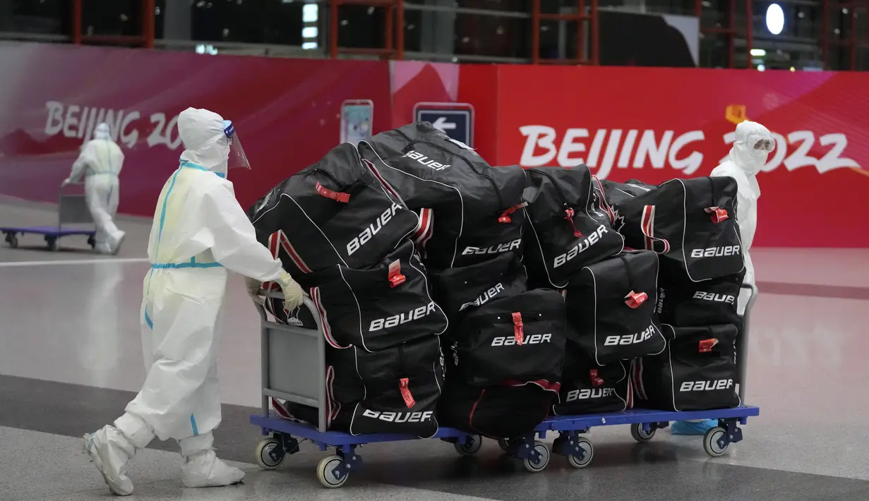Pekerja Olimpiade dengan pakaian pelindung membantu para pelancong di bandara Internasional Ibu Kota Beijing setelah Olimpiade Musim Dingin 2022, di Beijing, China, Senin (21/2/2022). (APhoto/Frank Augstein)