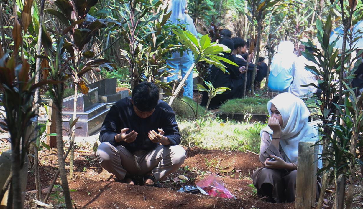 Warga datang bersama keluarga untuk mendoakan sanak saudara yang telah meninggal dunia. Tampak dalam foto, warga saat melakukan ziarah kubur usai melaksanakan salat Idulfitri 1447 Hijriah di salah satu Tempat Pemakaman Umum (TPU), Cibinong, Kabupaten Bogor, Jawa Barat, Sabtu (21/3/2026). (Kapanlagi.com/Budy Santoso)
