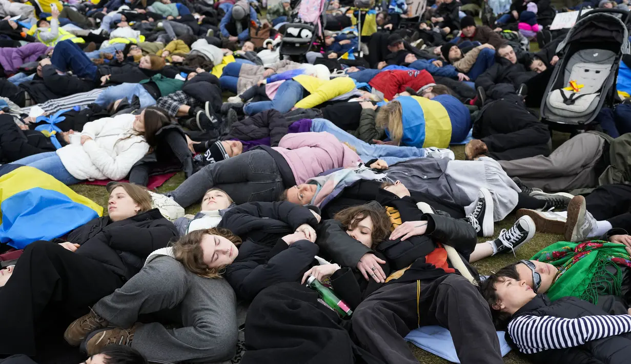 Orang-orang berbaring di tanah melambangkan mereka yang tewas dalam perang di Ukraina selama demonstrasi menentang invasi Rusia, dekat gedung parlemen Jerman, di Berlin, 6 April 2022. Pengunjuk rasa menuntut Berlin berhenti membeli minyak dan gas Rusia. (AP Photo/Markus Schreiber)