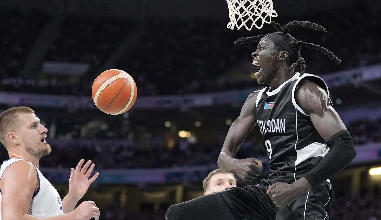 Pebasket Sudan Selatan Wenyen Gabriel (kanan) berselebrasi setelah melakukan dunk saat Nikola Jokic dari Serbia menonton selama pertandingan bola basket putra Olimpiade Paris 2024 di Villeneuve-d'Ascq, Sabtu, 3 Agustus 2024. (AP Photo/Michael Conroy)