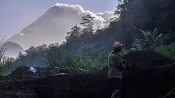 Seorang pria bekerja di lokasi penambangan pasir saat Gunung Merapi mengeluarkan abu vulkanik di Yogyakarta, Indonesia, (22/5).  Pihak berwenang juga memerintahkan warga dalam jarak 3 kilometer (2 mil) untuk mengungsi. (AP Photo/Slamet Riyadi)