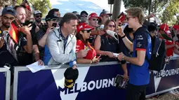 Pembalap Toro Rosso, Brandon Hartley memberikan tanda tangan kepada fans sesaat sebelum latihan bebas Formula 1 (F1) GP Australia di Melbourne, Jumat (23/3). Balapan F1 GP Australia 2018 sendiri akan bergulir pada Minggu, 25 Maret besok. (AP/Rick Rycroft)