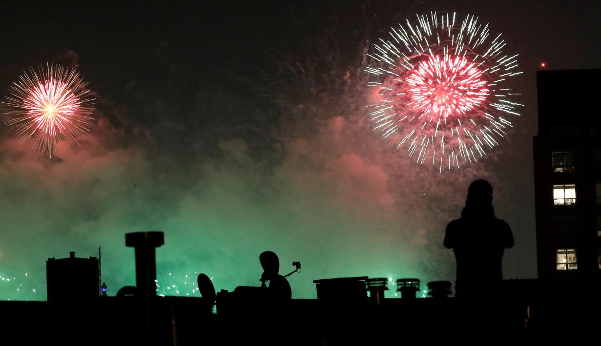 Seorang pria mengambil gambar kembang api yang meledak di udara pada perayaan Hari Kemerdekaan Amerika Serikat di New York City, Rabu (4/7).  AS merayakan hari kemerdekaan yang jatuh pada 4 Juli atau dikenal Independence Day 4th July. (AP/Julio Cortez)