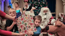 Anak-anak menerima hadiah saat acara Natal untuk anak-anak keluarga militer di Bucharest, Rumania, (21/12). Para ayah anak-anak tersebut sedang bertugas melayani misi pemelihara perdamaian internasional di National Military Circle. (AP Photo/Vadim Ghirda)