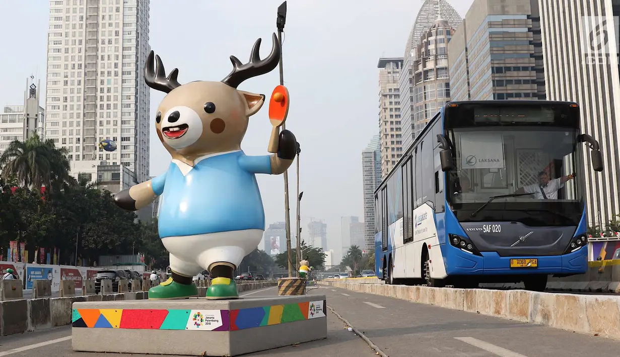 Bus Transjakarta melintas di samping patung maskot Asian Games 2018 yang menghiasi Jalan Sudirman, Jakarta, Rabu (8/8). Pemasangan maskot tersebut untuk menyemarakan Asian Games 2018 yang akan dibuka 18 Agustus 2018. (Liputan6.com/Immanuel Antonius)