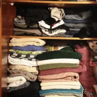 Kucing dalam tumpukan baju di lemari pakaian.