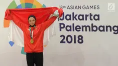 Pesilat Indonesia Sarah Tria Monita mengangkat bendera Merah Putih usai menaklukkan Nong Oy Vongphakdy asal Laos dalam babak final Kelas C Putri Asian Games 2018 di Jakarta, Senin (27/8). Sarah menang dan mendapatkan medali emas. (Merdeka.com/Arie Basuki)
