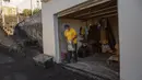Warga membersihkan pasir dan abu dari rumahnya, yang terletak di zona eksklusi setelah letusan gunung berapi Cumbre Vieja di lingkungan Las Manchas, Pulau La Palma, Spanyol pada 4 Januari 2022. Sekitar 1.000 orang diizinkan pulang minggu ini, dari total 7.000 yang dievakuasi. (DESIREE MARTIN/AFP)