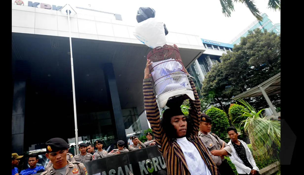 Seorang Seniman melakukan aksi teatrikal menaruh kandung burung di atas kepalanya di depan Gedung Komisi Pemberantasan Korupsi (KPK), Jakarta, Senin (26/1/2014). (Liputan6.com/Herman Zakharia)