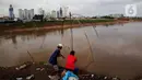 Warga menarik jala ikan dari tepi Banjir Kanal Barat, Tanah abang, Jakarta, Sabtu (4/1/2020). Debit air yang mulai surut di aliran tersebut dimanfaatkan warga untuk mencari ikan. (Liputan6.com/Angga Yuniar)