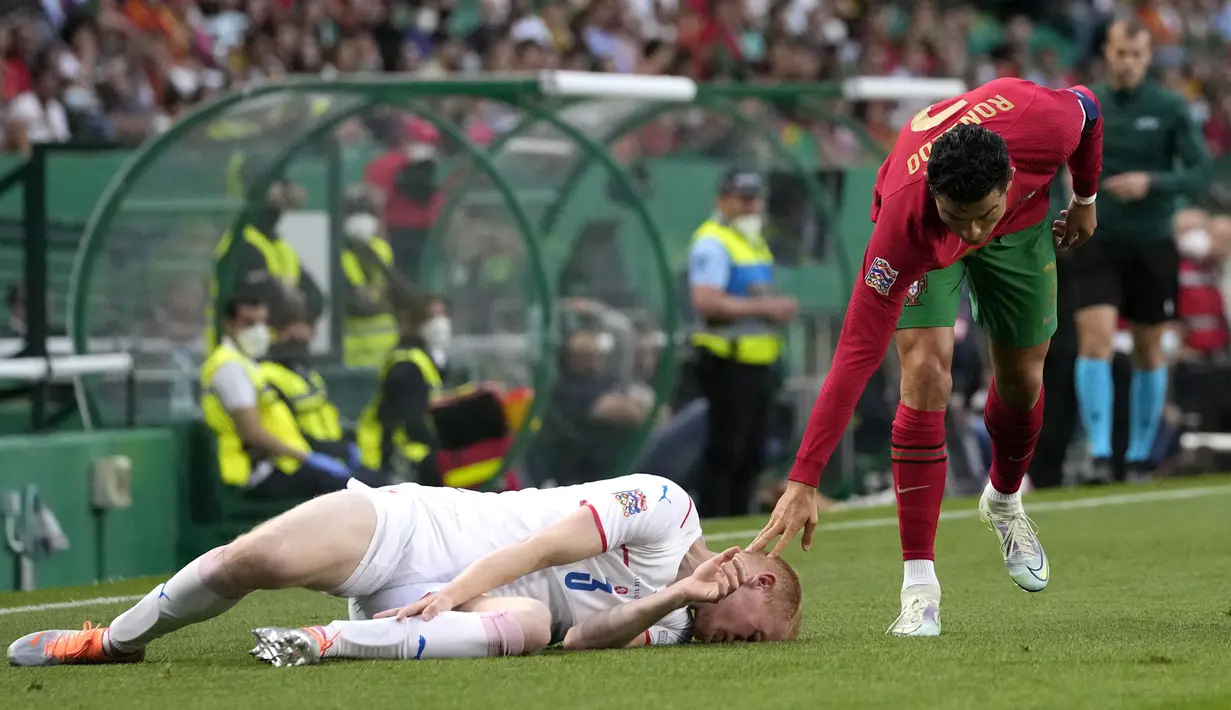 Pemain Portugal Cristiano Ronaldo (kanan) memeriksa pemain Republik Ceko Vaclav Jemelka saat dia berbaring di lapangan pada pertandingan sepak bola UEFA Nations League di Stadion Jose Alvalade, Lisbon, Portugal, 9 Juni 2022. Portugal menang 2-0. (AP Photo/Armando Franca)