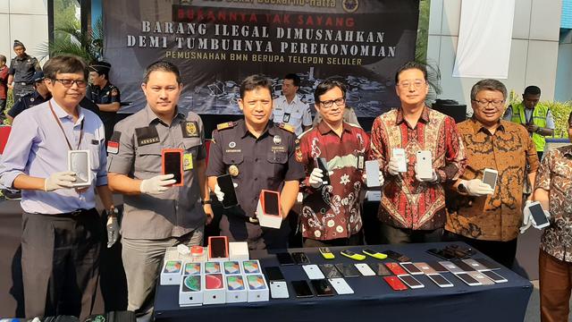 Sebanyak 2.464 unit smartphone senilai Rp 3.5 miliar sitaan Kantor Pelayanan Utama Bea dan Cukai Tipe C Soekarno Hatta, dimusnahkan dengan cara direndam semalaman di air garam dan dilindas alat berat, Selasa (8/10/2019).