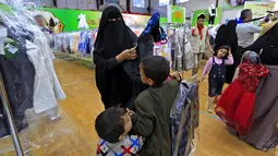 Anak-anak Yaman mengenakan pakaian baru selama pembagian pakaian amal di stadion di ibu kota Sanaa (25/4/2021). Pembagian pakaian amal bagian dari tindakan untuk membantu orang miskin selama bulan suci puasa Ramadhan. (AFP/Mohammed Huwais)
