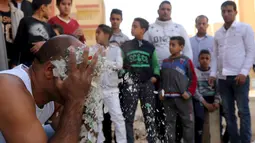Karim Hussein mengusap wajahnya dengan pecahan kaca saat unjuk kebolehan di Kairo (18/3/2016). Warga sekitar tampak menonton aksi mengerikan dari Karim Hussein "The Pharaoh"  (Reuters/ Mohamed Abd El Ghany)