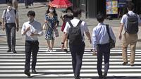 Orang-orang yang memakai masker melintasi persimpangan di Tokyo Kamis (5/8/2021). Tokyo pada hari Kamis melaporkan 5.042 kasus virus corona baru, rekor tertinggi harian terbaru sejak pandemi Covid-19 dimulai, di saat ibu kota Jepang menjadi tuan rumah Olimpiade. (AP Photo/Kantaro Komiya)