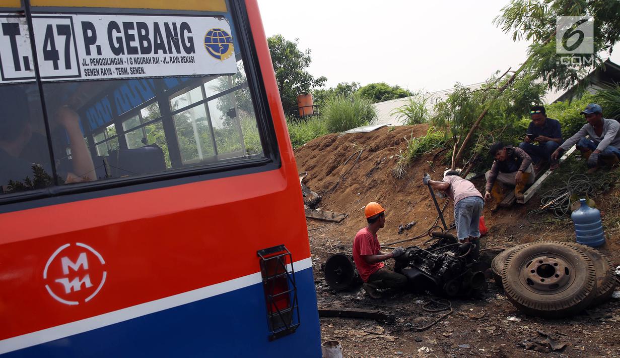 Pekerja memotong bagian mesin dari angkutan Metromini di salah satu pool Metromini, Jalan Pulogebang, Jakarta, Rabu (3/1). Satu unit bangkai metromini ini dihargai senilai Rp12 juta oleh pengepul besi bekas. (Liputan6.com/JohanTallo)