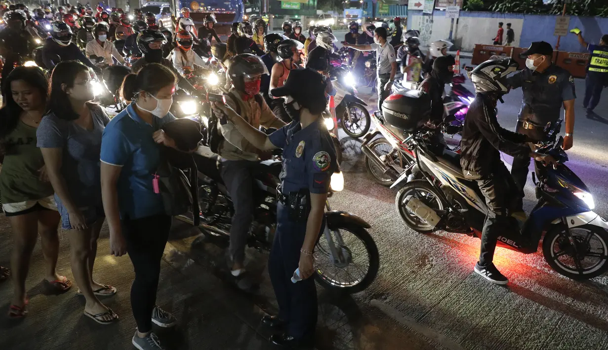 Polisi memeriksa suhu tubuh warga di pos pemeriksaan virus corona COVID-19 di Manila, Filipina, Senin (16/3/2020). Polisi beserta petugas lalu lintas dan petugas desa melakukan pengecekan suhu tubuh warga untuk mencegah penyebaran virus corona COVID-19. (AP Photo/Aaron Favila)