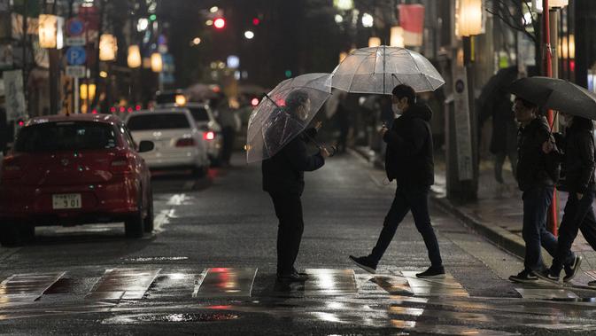 Seorang pria, tengah, bekerja untuk sebuah restoran berbicara kepada pejalan kaki untuk mempromosikan tokonya di Tokyo (5/3/2021). Status darurat seharusnya berakhir pada Minggu (7/3) dan sempat dicabut lebih awal di beberapa daerah lain di Jepang. (AP Photo/Hiro Komae)