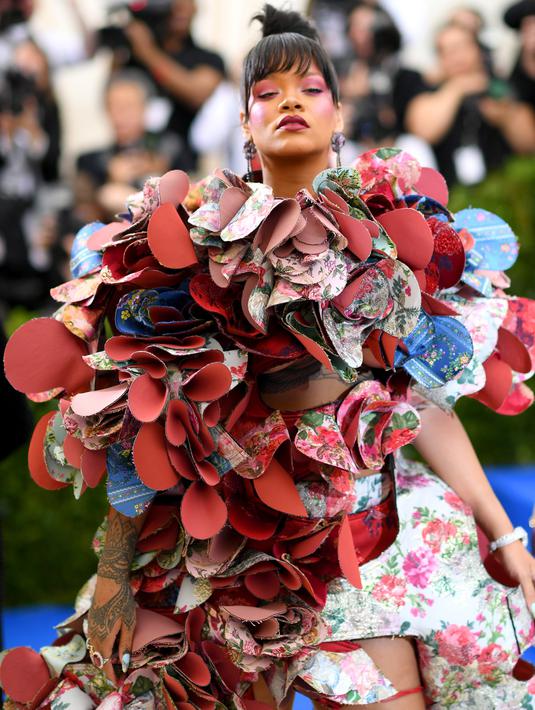 Penyanyi Rihanna berpose untuk fotografer setibanya di acara penggalangan dana Met Gala 2017, New York, Senin (1/5). Menyesuaikan tema Comme des Garcons, Rihanna tampil unik lewat gaun aksen bunga rancanangan Rei Kawakubo. (Dimitrios Kambouris/AFP)