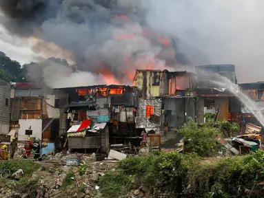 Petugas pemadam kebakaran berusaha memadamkan api yang membakar kawasan kumuh di Manila, Filipina (11/8). Api yang membakar pemukiman selama tiga jam tersebut menelan 300 rumah. (AP Photo/Bullit Marquez)