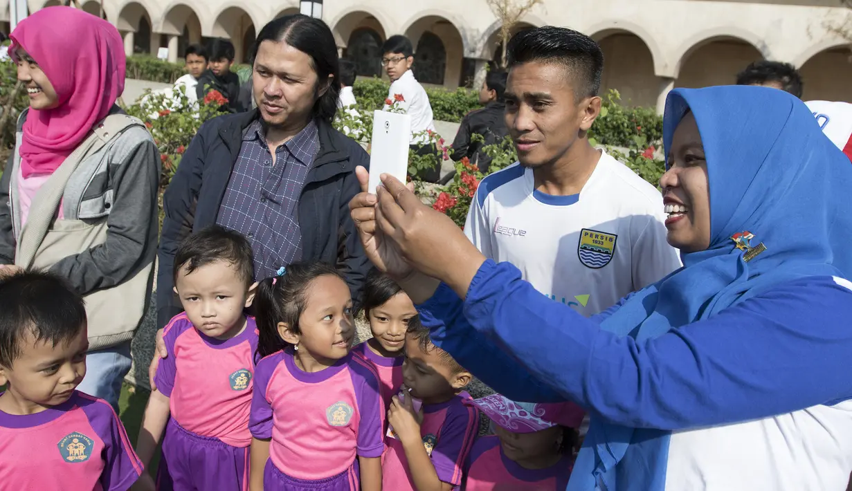Pemain Persib, Muhammad Taufiq melakukan selfie bersama anak-anak SD usai latihan di Alun-alun Kota Bandung, Jawa Barat, Kamis (10/9/2015). (Bola.com/Vitalis Yogi Trisna)